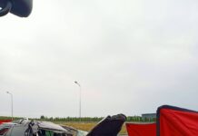 Zniszczony samochód osobowy leży na poboczu drogi, otoczony przez czerwone namioty i taśmy zabezpieczające.