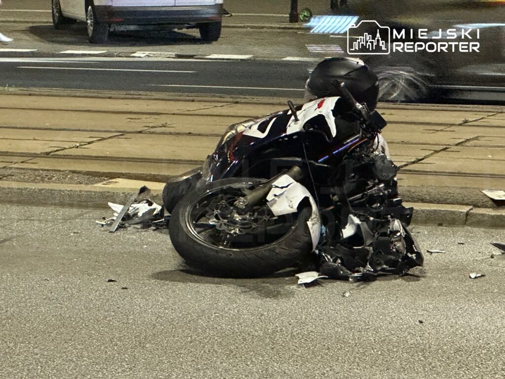 Zniszczony motocykl leży na jezdni obok torów tramwajowych po wypadku.