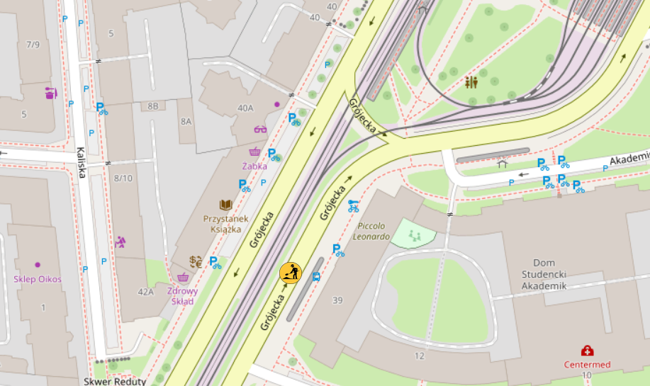 Mapa przedstawiająca ulice i budynki w okolicy, z lokalizacjami parkingów oraz punktami usługowymi.
