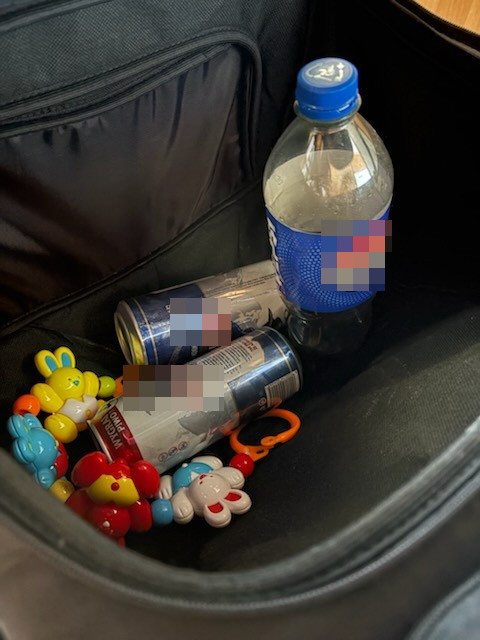 Wnętrze torby z plastikową butelką, dwoma puszkami napoju energetycznego i kolorowymi zabawkami dla dzieci.