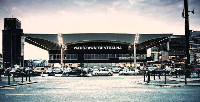 Warszawska stacja kolejowa z dużą przestrzenią parkingową i nowoczesną architekturą.