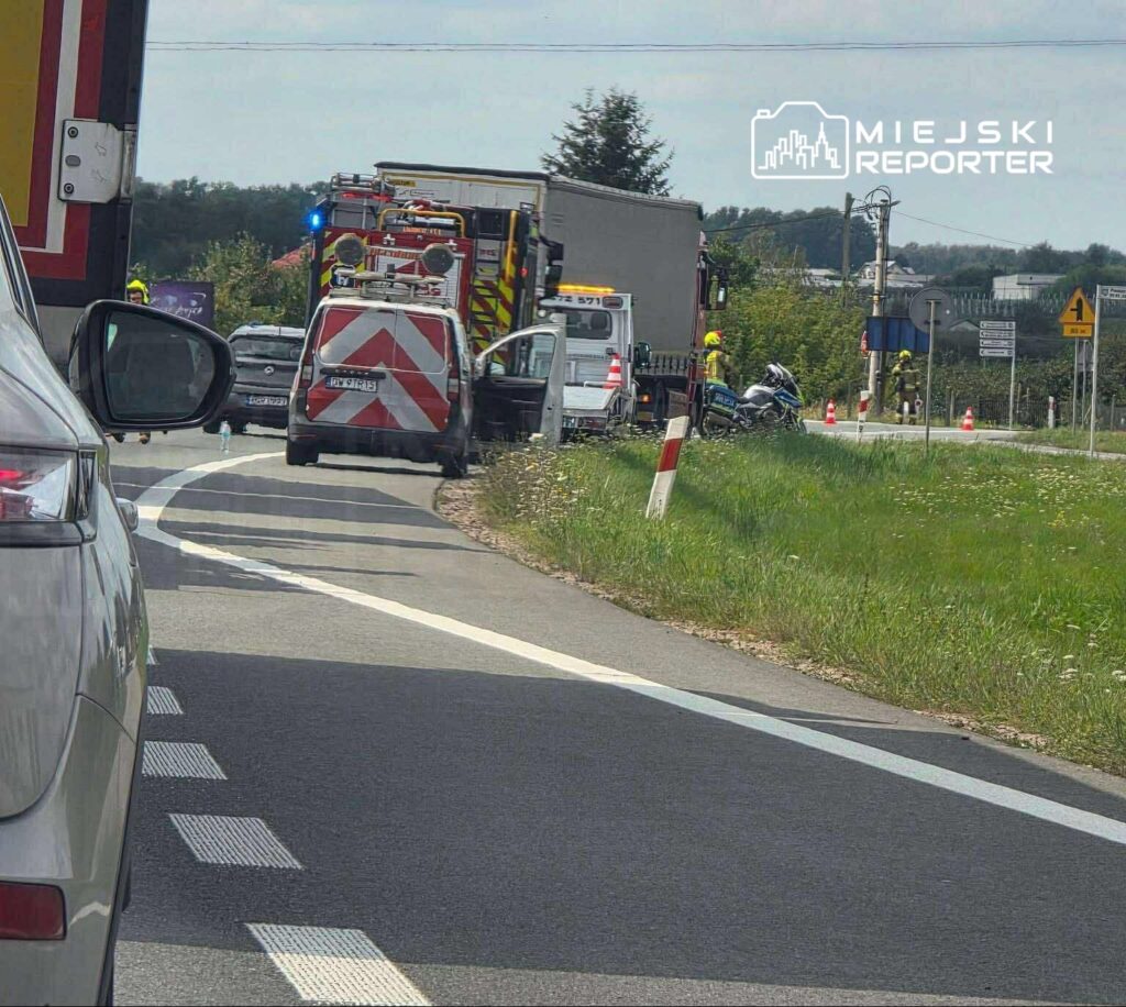 Na drodze stoi kilka pojazdów ratunkowych, a strażacy oraz policja zabezpieczają miejsce zdarzenia.
