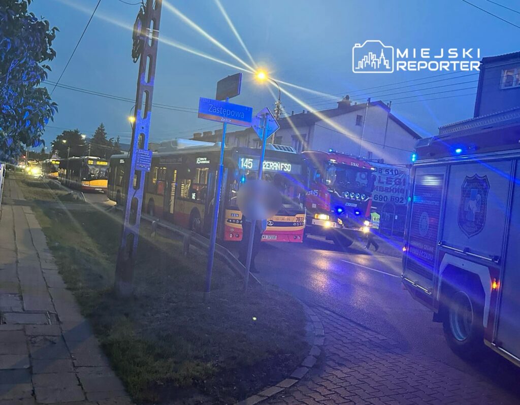 Pojazdy ratunkowe z włączonymi sygnałami świetlnymi na ulicy Zastepowej, obok przystanku autobusowego.