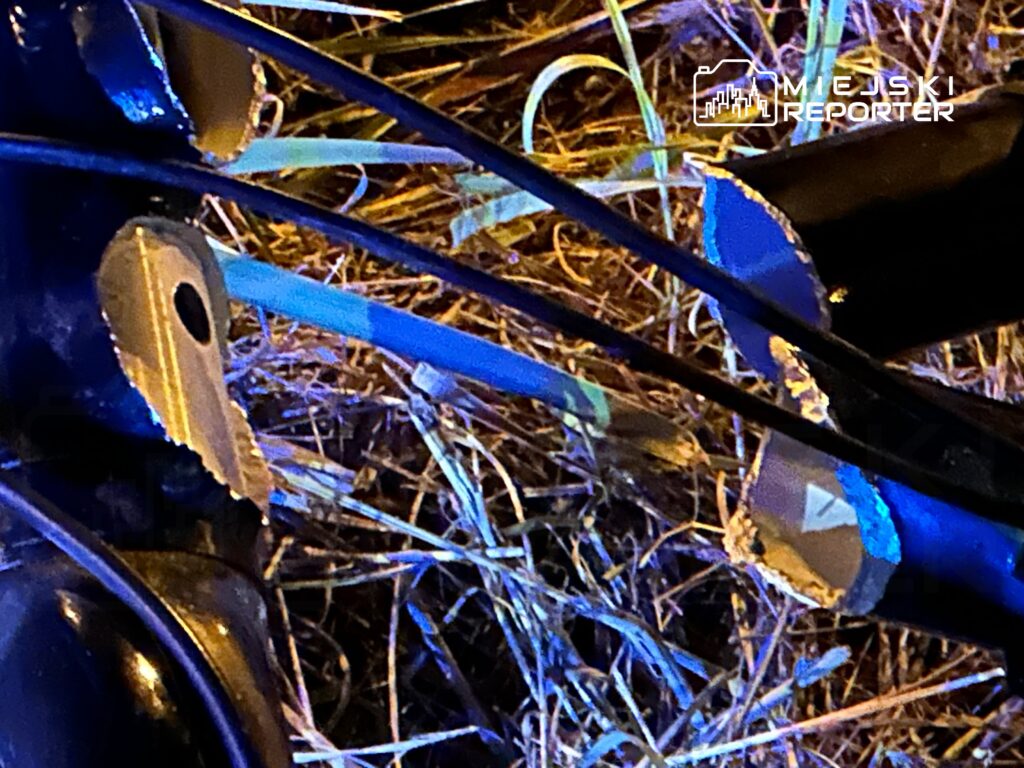 Złamany kawałek metalowej konstrukcji leży na trawie, z widocznymi uszkodzeniami i odłamkami.