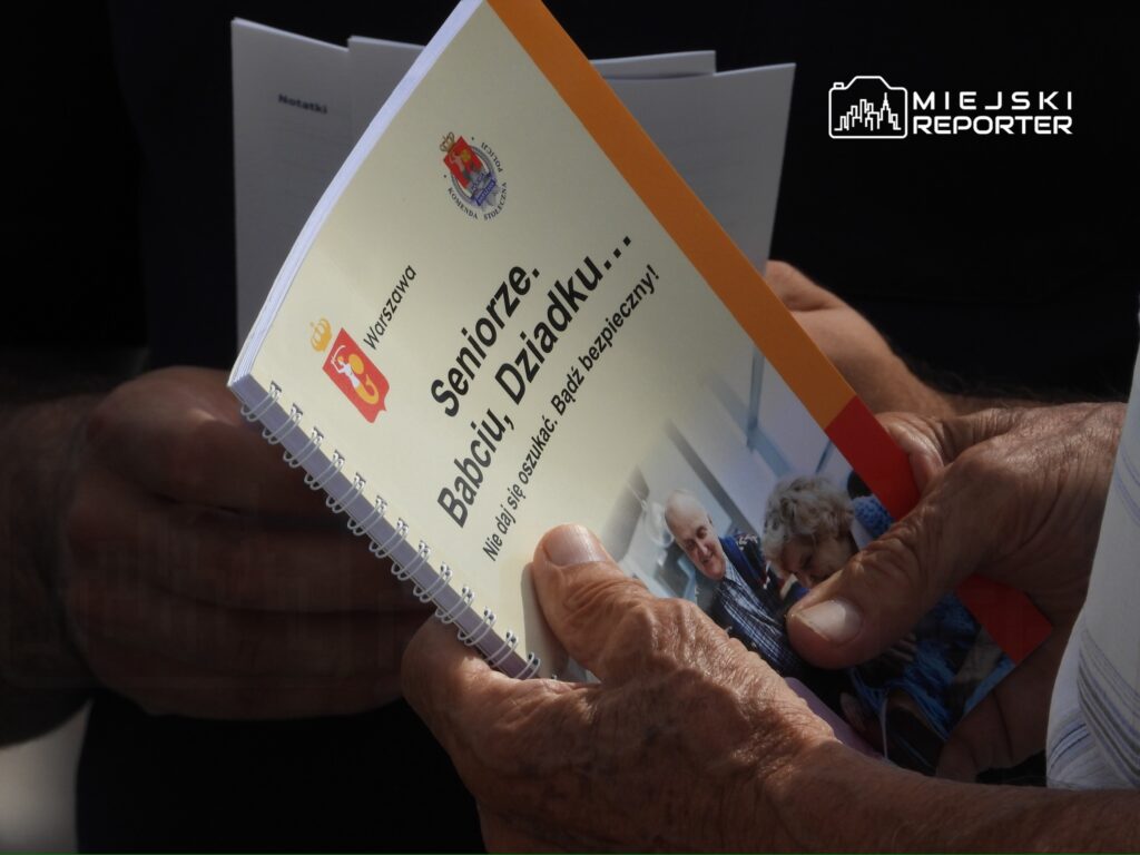 Mężczyzna trzyma broszurę "Seniorze, Babciu, Dziadku..." z informacjami o bezpieczeństwie dla seniorów.