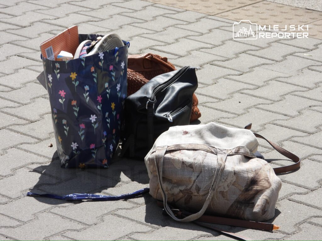 Kilka toreb leży na chodniku, w tym torba z kwiatowym wzorem, skórzana torebka i materiałowa torba z nadrukiem.