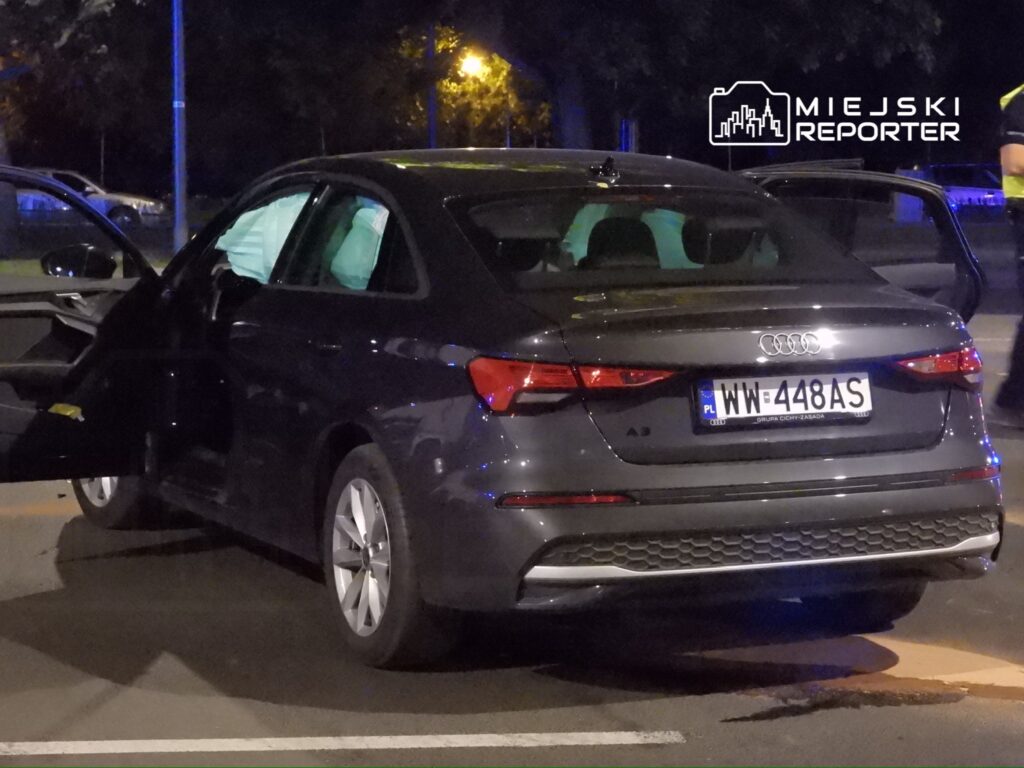 Czarny samochód marki Audi A3 z otwartymi drzwiami, zaparkowany na ulicy w nocy.