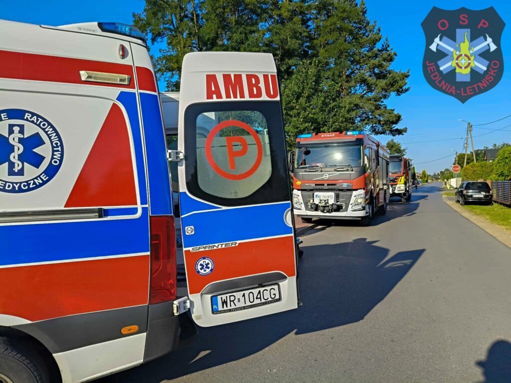 Karetka pogotowia oraz dwa wozy strażackie zaparkowane na ulicy w spokojnej okolicy.