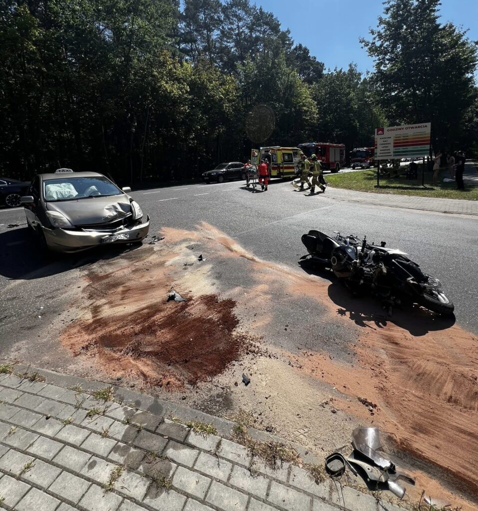 Wypadek drogowy z udziałem samochodu osobowego i motocykla na ulicy, z widocznymi śladami na jezdni. Obecni ratownicy medyczni.