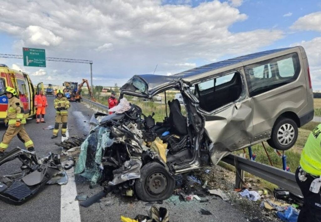 Wielki wypadek drogowy z rozbitym pojazdem na autostradzie, wokół strażacy i ratownicy medyczni.