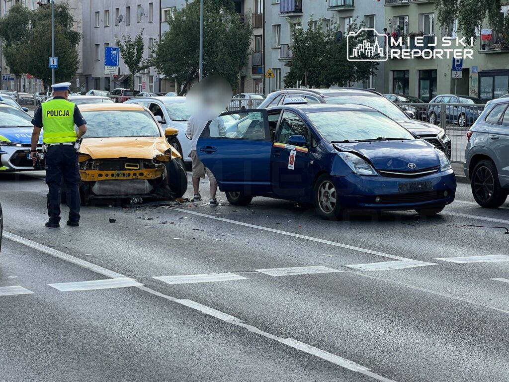 Policjant w kamizelce odblaskowej bada miejsce wypadku drogowego, gdzie zderzyły się dwa samochody.