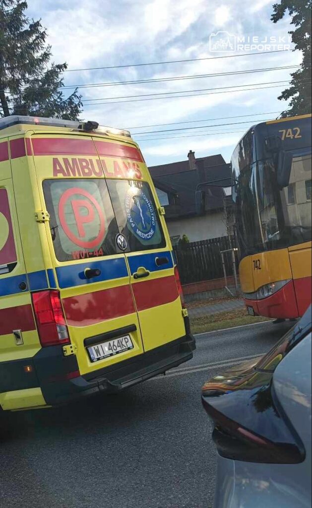 Karetka pogotowia z widocznym napisem "AMBULANS" stoi na drodze obok przystanku autobusowego z numerem 742.
