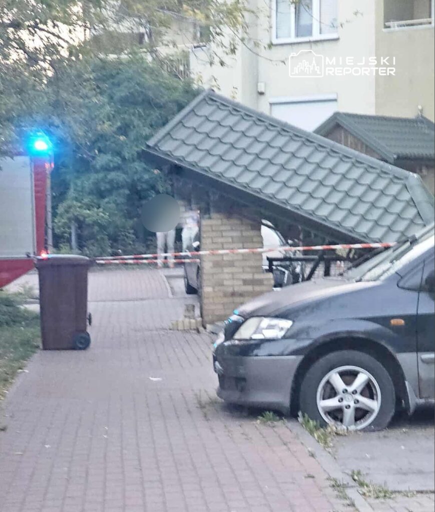 Zniszczony daszek altany ogrodowej leży na boku, otoczony taśmą ostrzegawczą i samochodem zaparkowanym na chodniku.