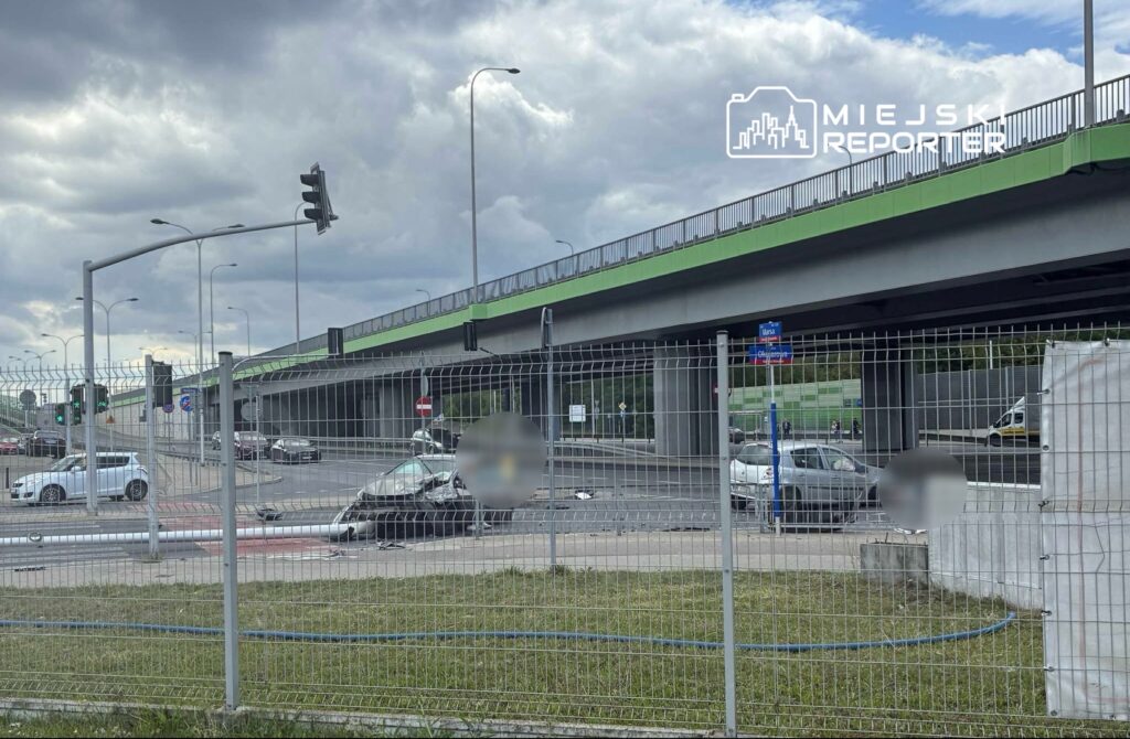 Ruch samochodowy na skrzyżowaniu z sygnalizacją świetlną, w tle widoczny podjazd pod wiadukt.