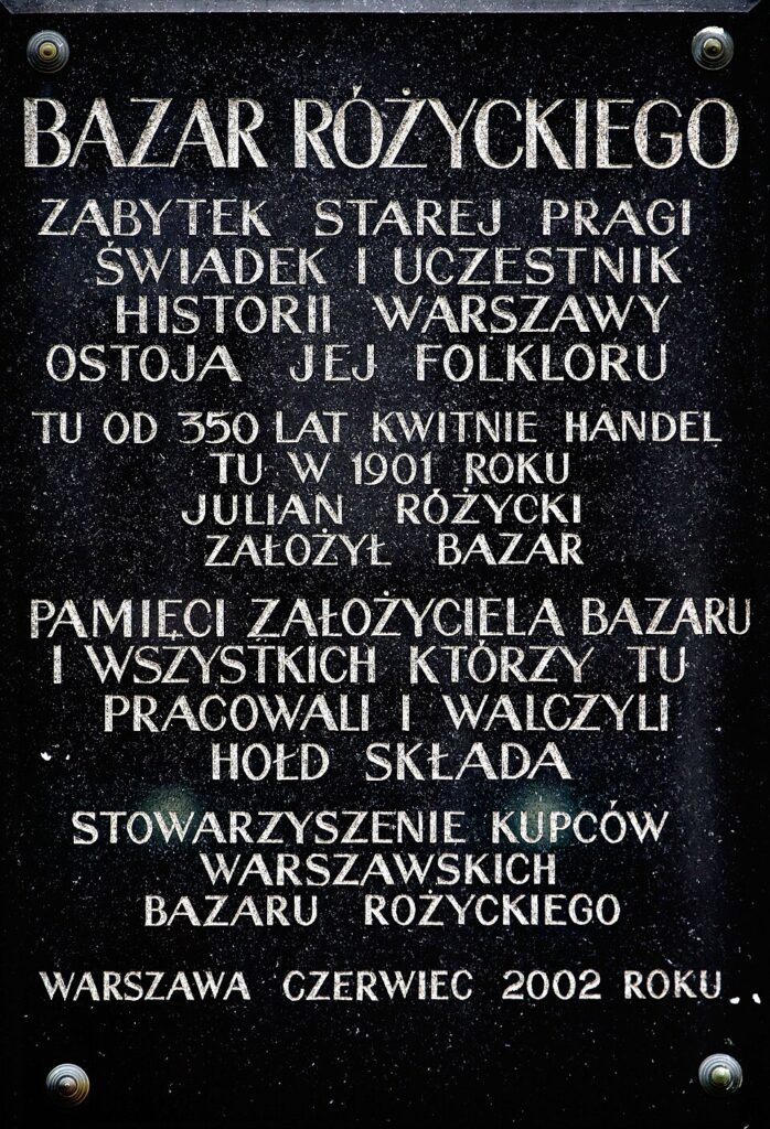 Pomnik z tekstem upamiętniającym Bazar Różyckiego w Warszawie, umieszczony na czarnej płycie.