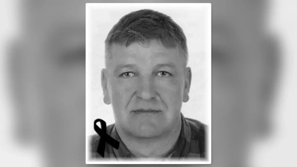 Człowiek z krótkimi włosami i poważnym wyrazem twarzy, na zdjęciu z czarną wstążką w rogu.