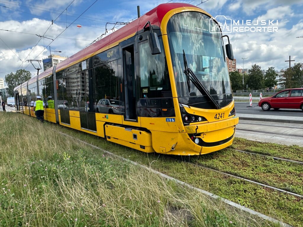 Tramwaj o numerze 4241 zatrzymany na torach, obok trwają prace drogowe i zielona trawa w otoczeniu miejskim.