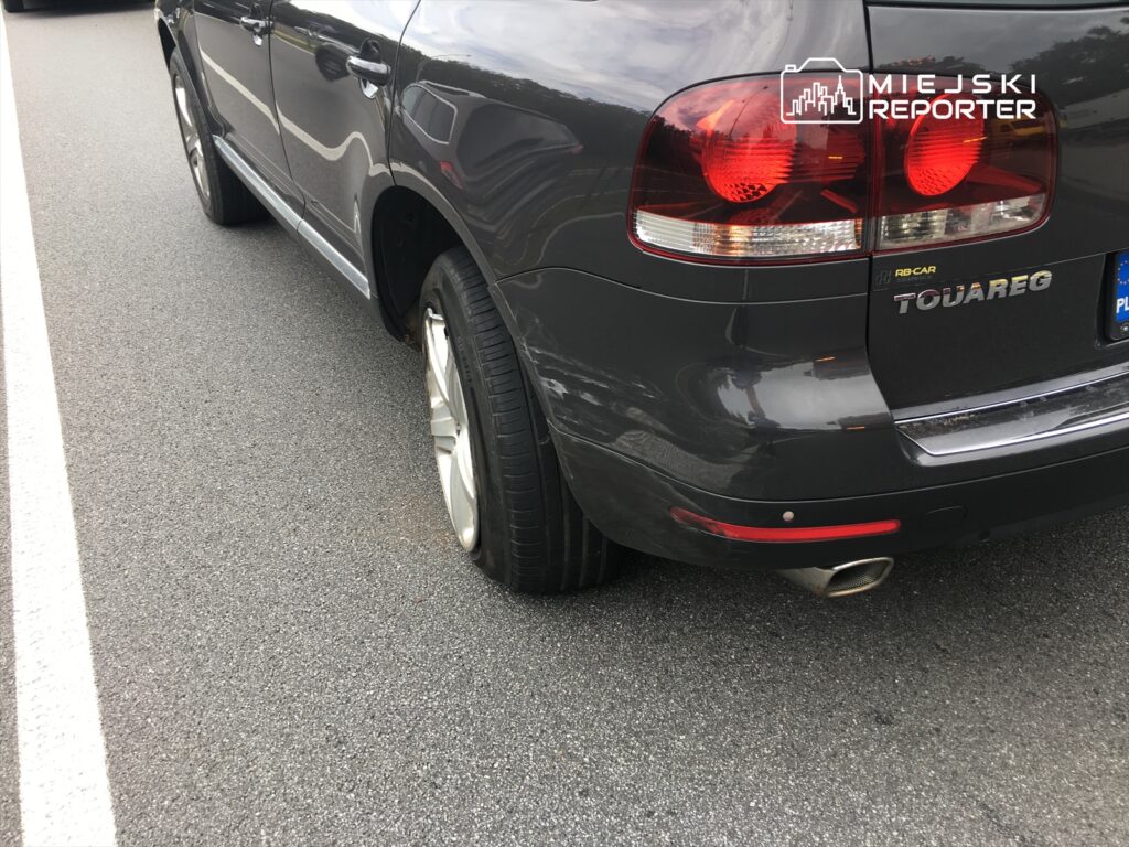 Samochód terenowy marki Volkswagen Touareg z uszkodzoną oponą zaparkowany na asfaltowej drodze.