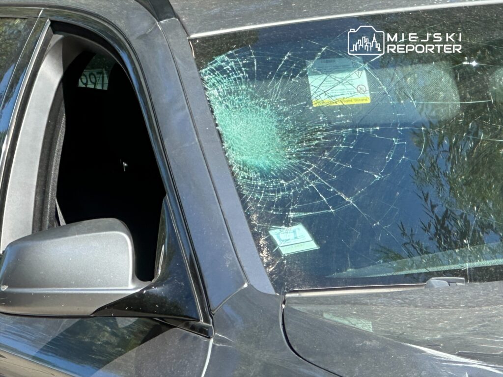 Pęknięta szyba przednia czarnego SUV-a z widocznymi odpryskami i uszkodzeniami w świetle dziennym.