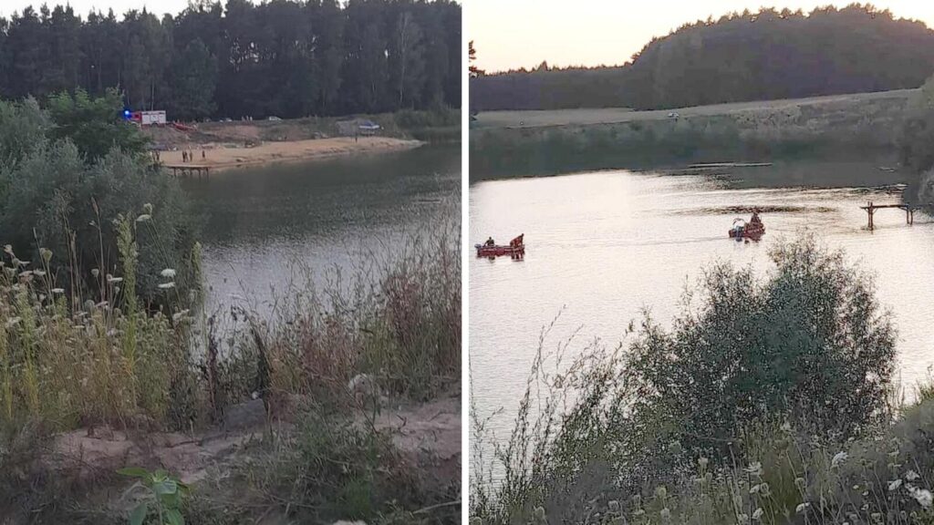 Grupa ludzi na plaży obserwuje akcję ratunkową na wodzie, gdzie łódź z ratownikami przeszukuje zbiornik.