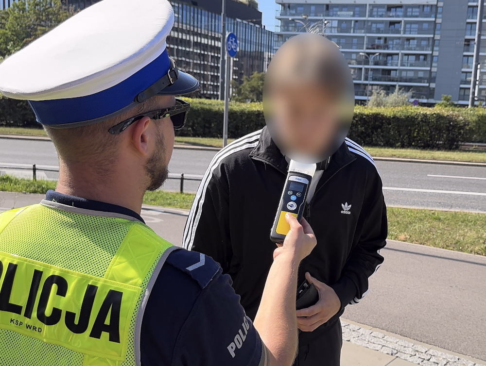Policjant przeprowadza kontrolę trzeźwości mężczyzny w odzieży sportowej na ulicy.