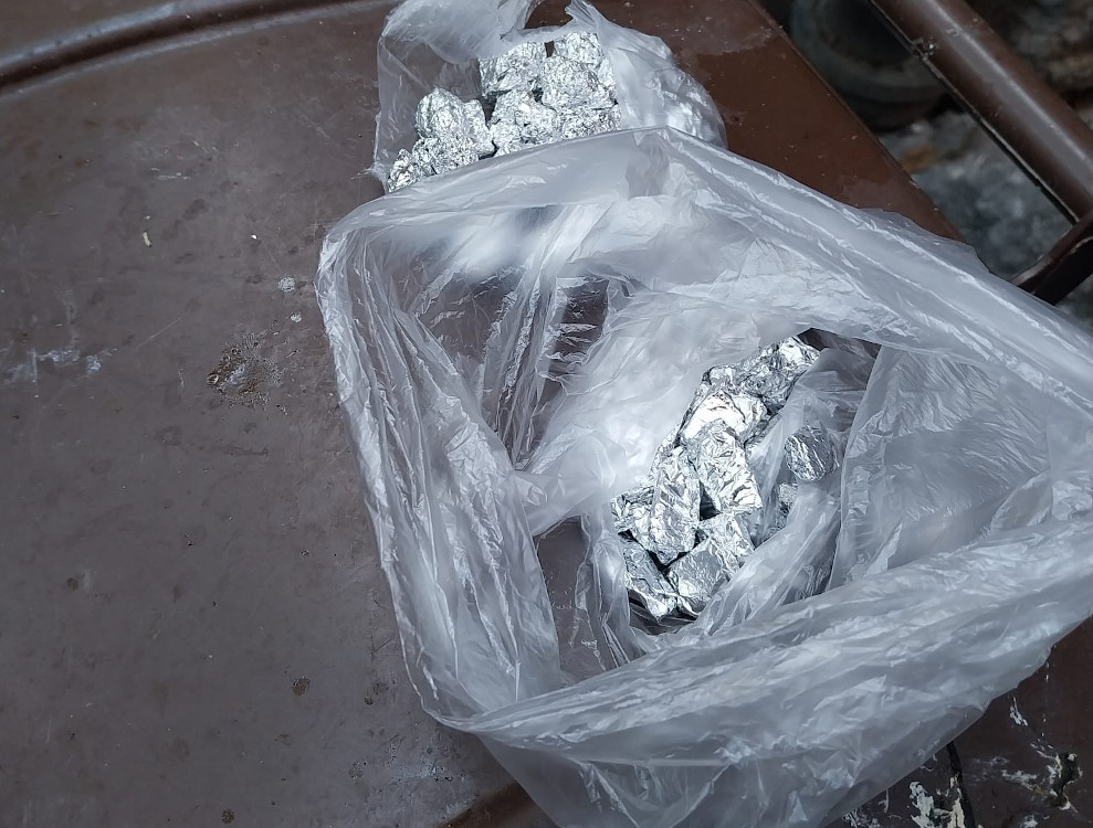 Sześć foliowych torebek z zawartością metalowych przedmiotów leży na brązowej powierzchni.