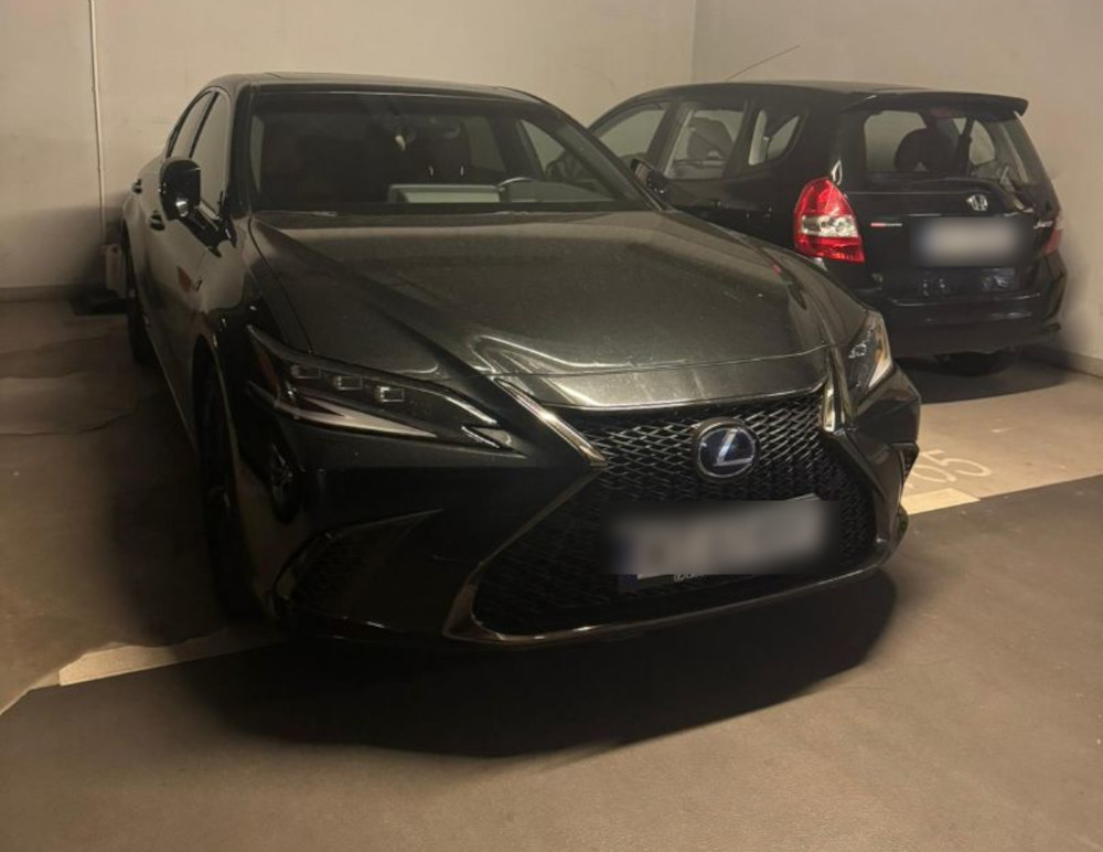 Czarny samochód marki Lexus zaparkowany w podziemnym garażu obok ciemnego pojazdu marki Honda.