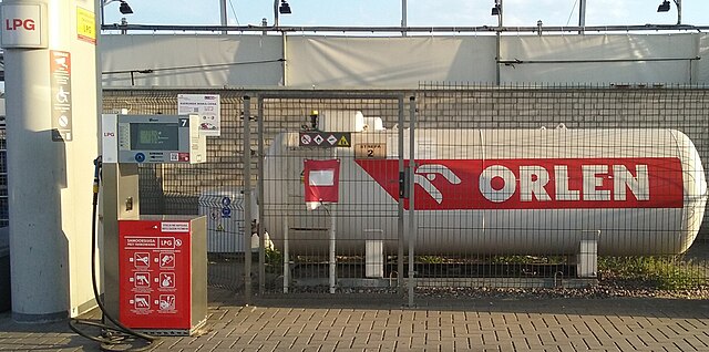 Stacja LPG z dystrybutorem oraz zbiornikiem gazu z logo Orlen w ogrodzeniu.