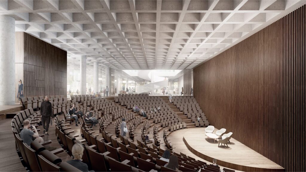 Nowoczesna sala konferencyjna z okrągłą sceną i rzędem krzeseł, wypełniona uczestnikami wydarzenia.