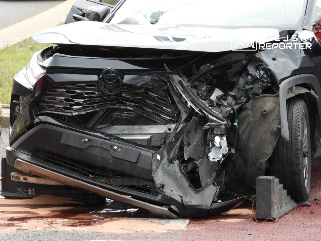 Czarny SUV z uszkodzoną przednią częścią stoi na drodze, obok widoczny ślad płynów.