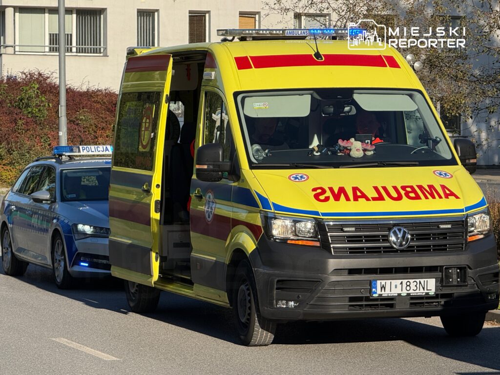 Karetka pogotowia z otwartymi drzwiami stoi obok radiowozu policyjnego na ulicy w mieście.