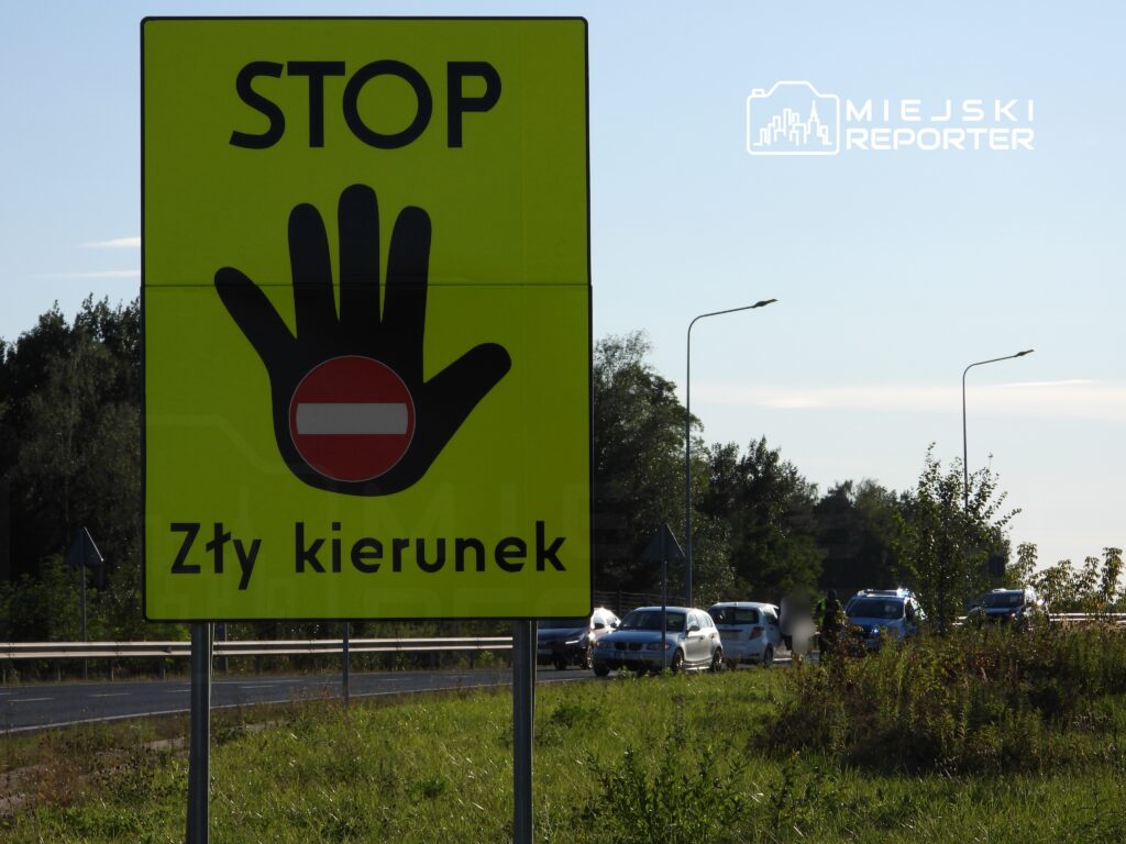 Żółty znak drogowy z napisem "STOP" i symbolem zakazu wjazdu informuje o złym kierunku na drodze.