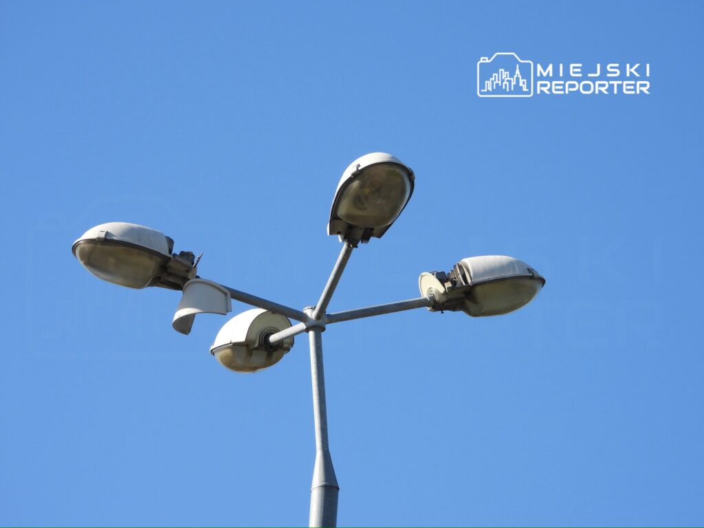Lampa uliczna z czterema reflektorami na tle błękitnego nieba.