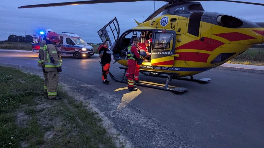 Ratownicy medyczni przygotowują się do transportu pacjenta helikopterem ratunkowym na drodze.