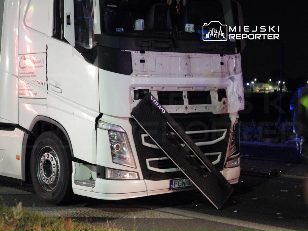 Ciężarówka marki Volvo z uszkodzonym przodem stoi na drodze, obok leży odłączony zderzak.