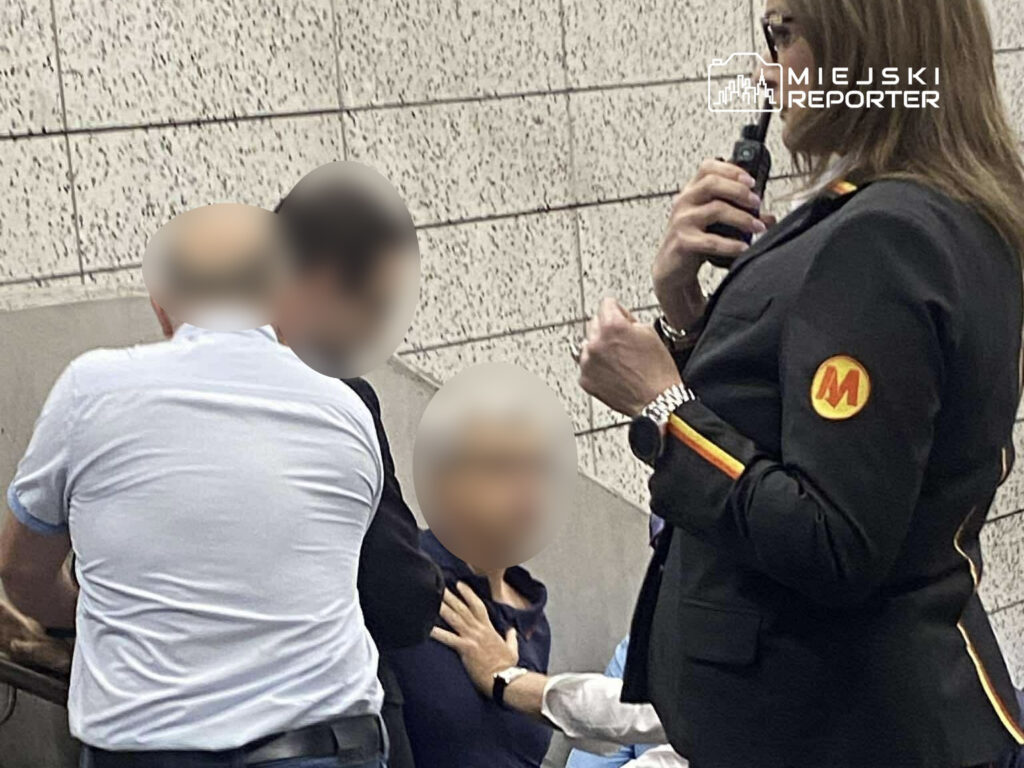 Kobieta w uniformie z logo rozmawia przez radio, podczas gdy mężczyzna pomaga innej osobie siedzącej na ławce.