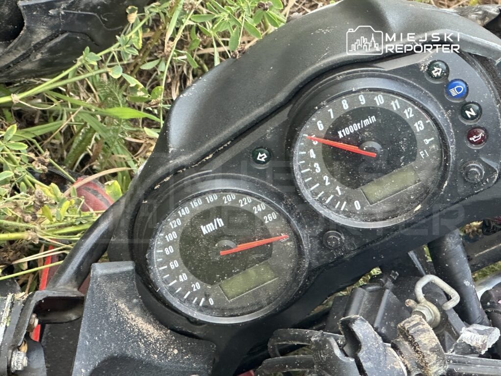 Zbliżenie na deski rozdzielcze motocykla, z widocznymi wskaźnikami prędkości i obrotów, pokrytymi kurzem.