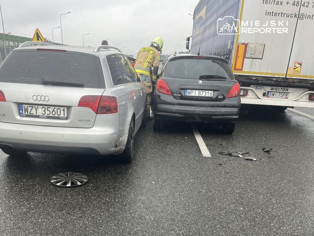 Wielu ratowników medycznych pracuje przy stłuczce dwóch samochodów osobowych na mokrej nawierzchni drogi.