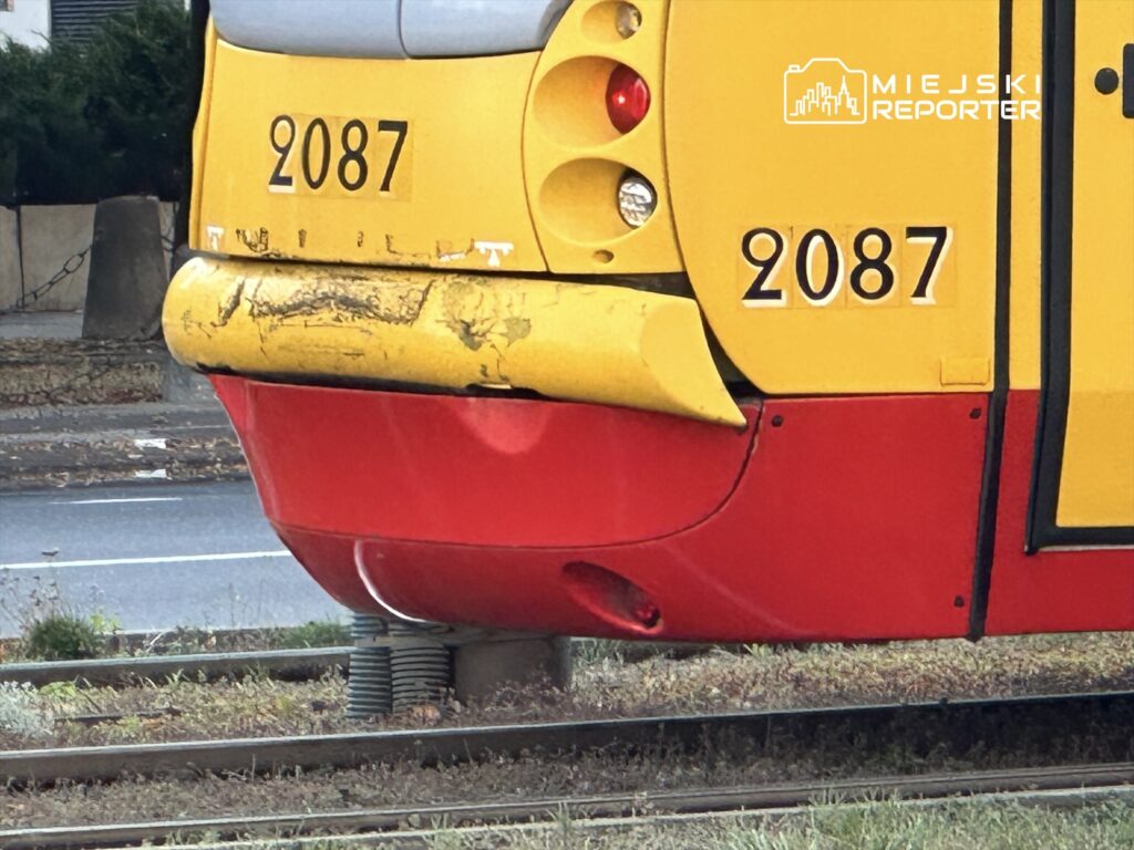 Zbliżenie na tylną część tramwaju w kolorze żółto-czerwonym z numerem 2087, stojącego na torach.