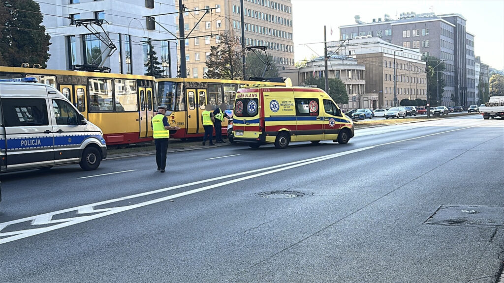 Na ulicy stoi karetka pogotowia oraz radiowóz policji, a funkcjonariusze rozmawiają przy tramwaju.