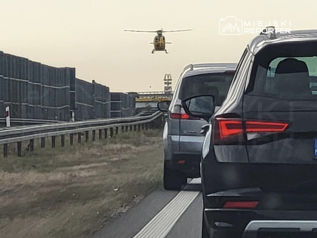 Helikopter przelatujący nad zatorami drogowymi na autostradzie, w tle widoczny znak McDonald's.