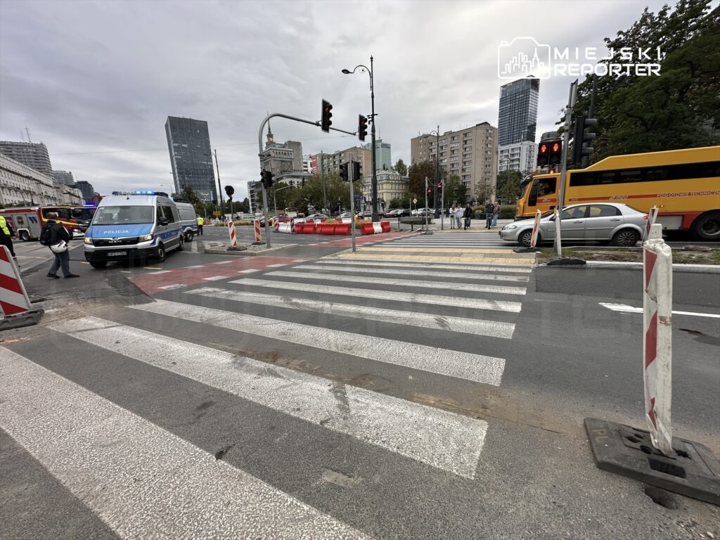 Policyjny furgon z włączonymi sygnałami świetlnymi zatrzymany przy przejściu dla pieszych w miejskim otoczeniu.