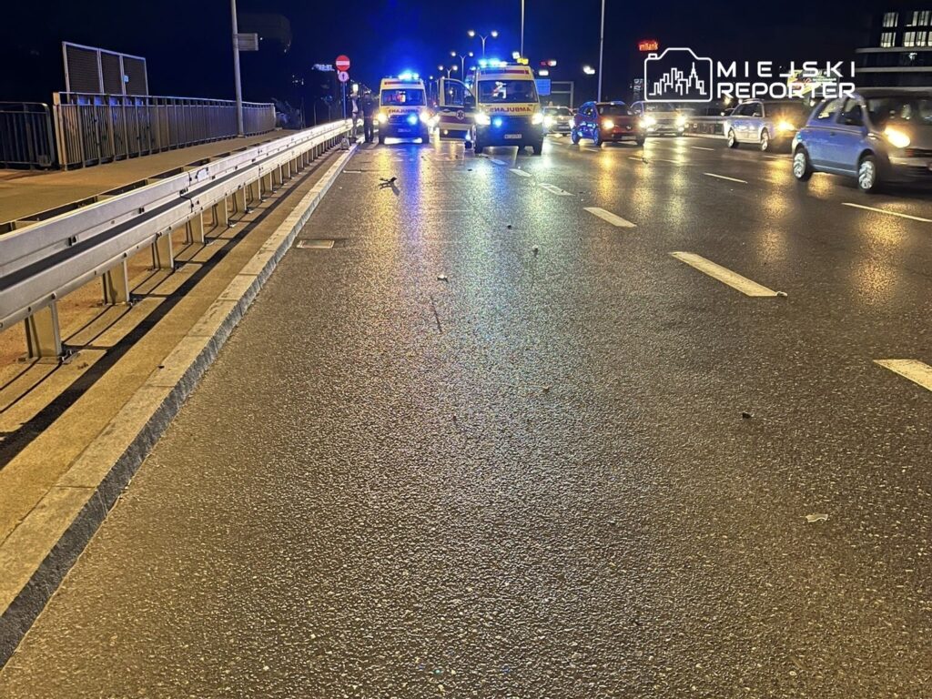 Na jezdni w nocy stoją karetki pogotowia, a w tle widać samochody poruszające się w obie strony.
