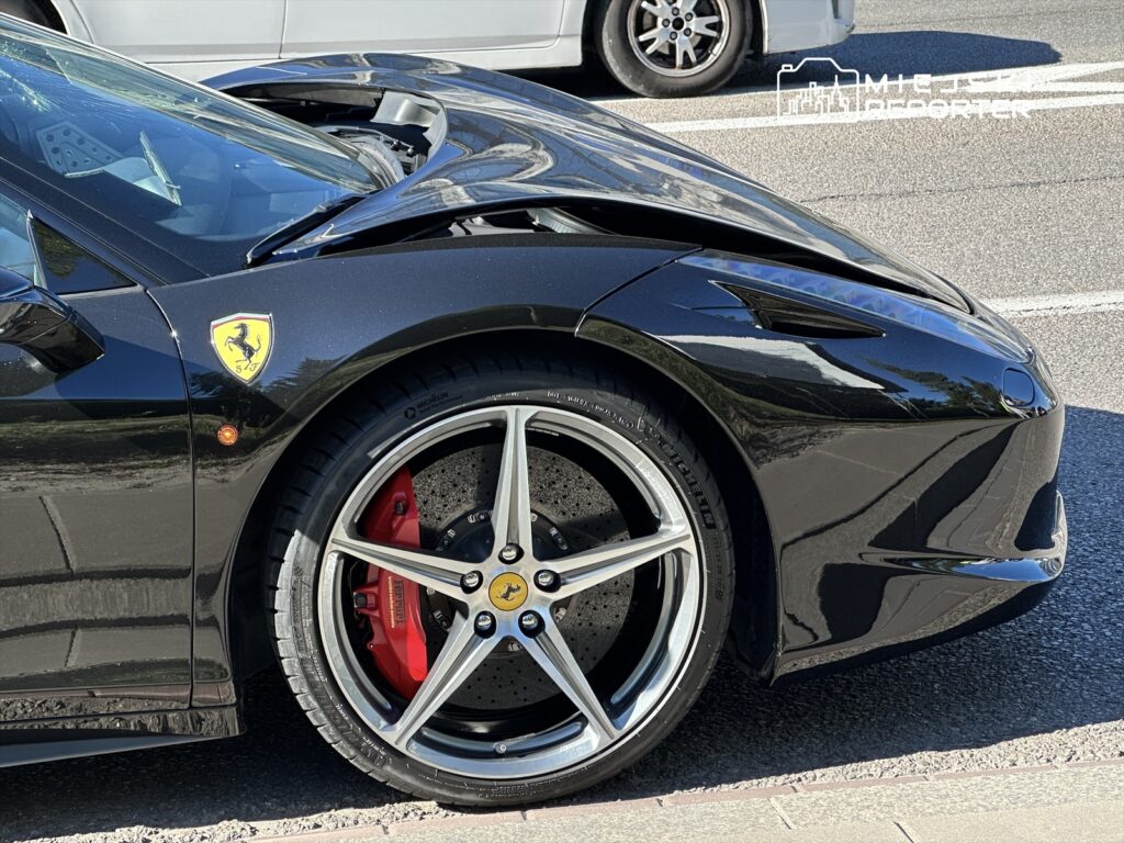 Czarny samochód sportowy marki Ferrari z otwartą maską, widoczne czerwone zaciski hamulcowe i aluminiowe felgi.