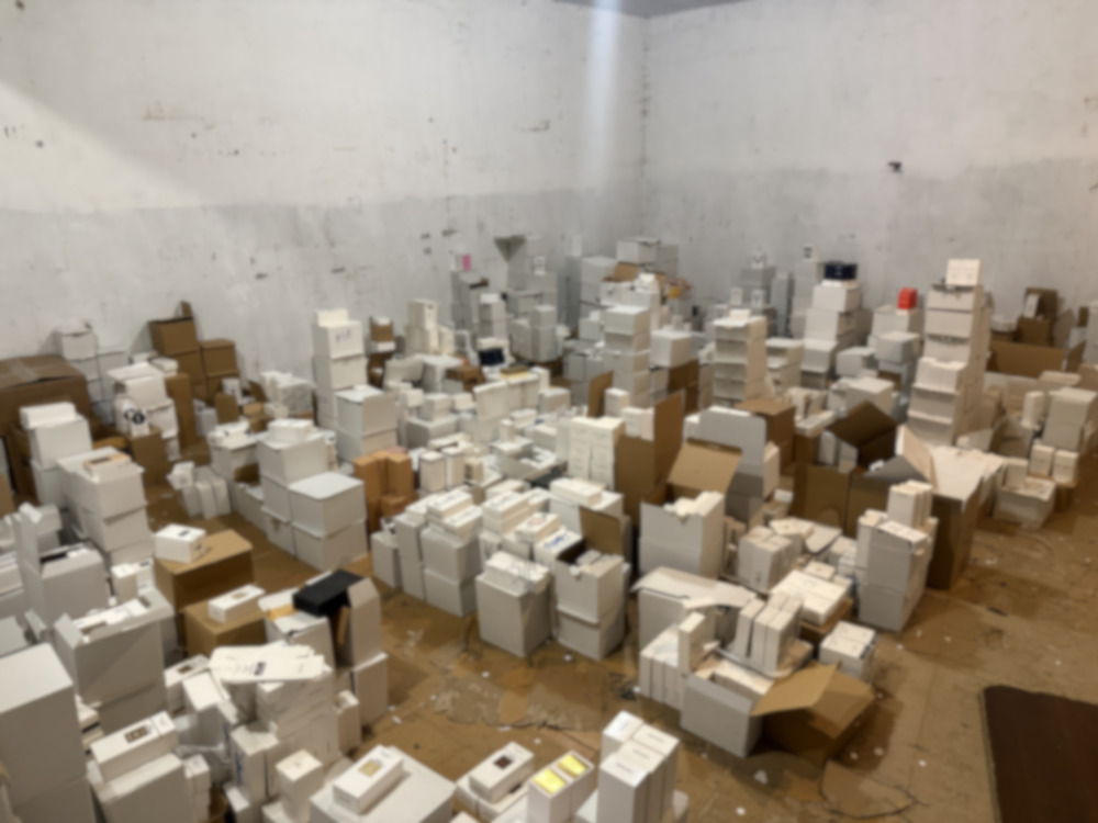 Pomieszczenie z dużą ilością kartonów i pudełek w różnych rozmiarach, porozrzucanych po podłodze.