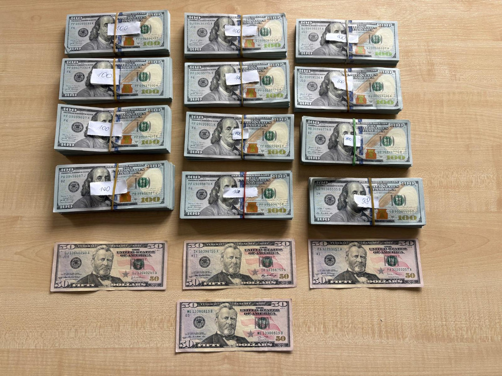 Stosy banknotów amerykańskich o nominałach 100 i 50 dolarów ułożone na drewnianym blacie.