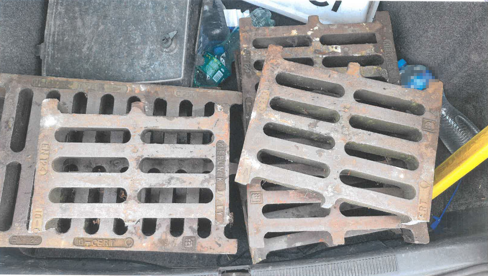 W bagażniku samochodu znajdują się metalowe kratki, obok nich leżą plastikowe butelki i narzędzia.