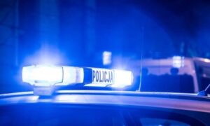 Niebieskie światła policyjne migają na dachu radiowozu w nocy.