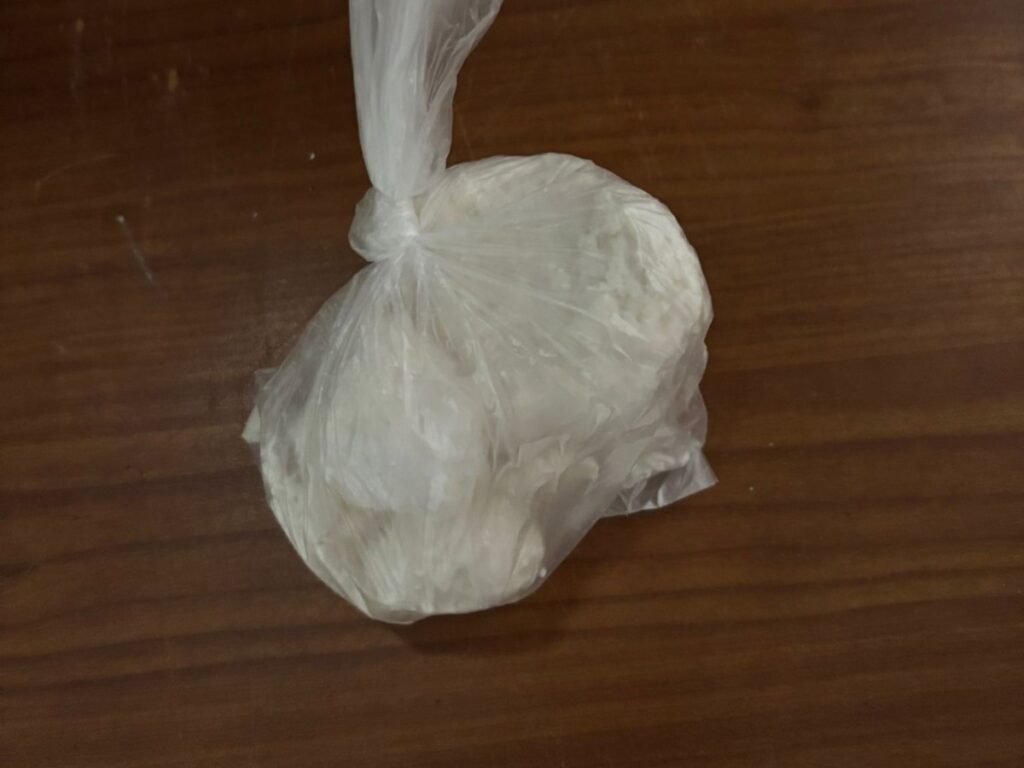 Biały, plastikowy worek z zawartością leży na drewnianym blacie.