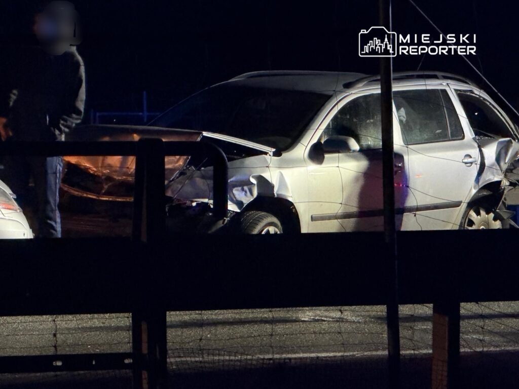 Mężczyzna w ciemnym ubraniu ogląda uszkodzone samochody na drodze, w nocy.